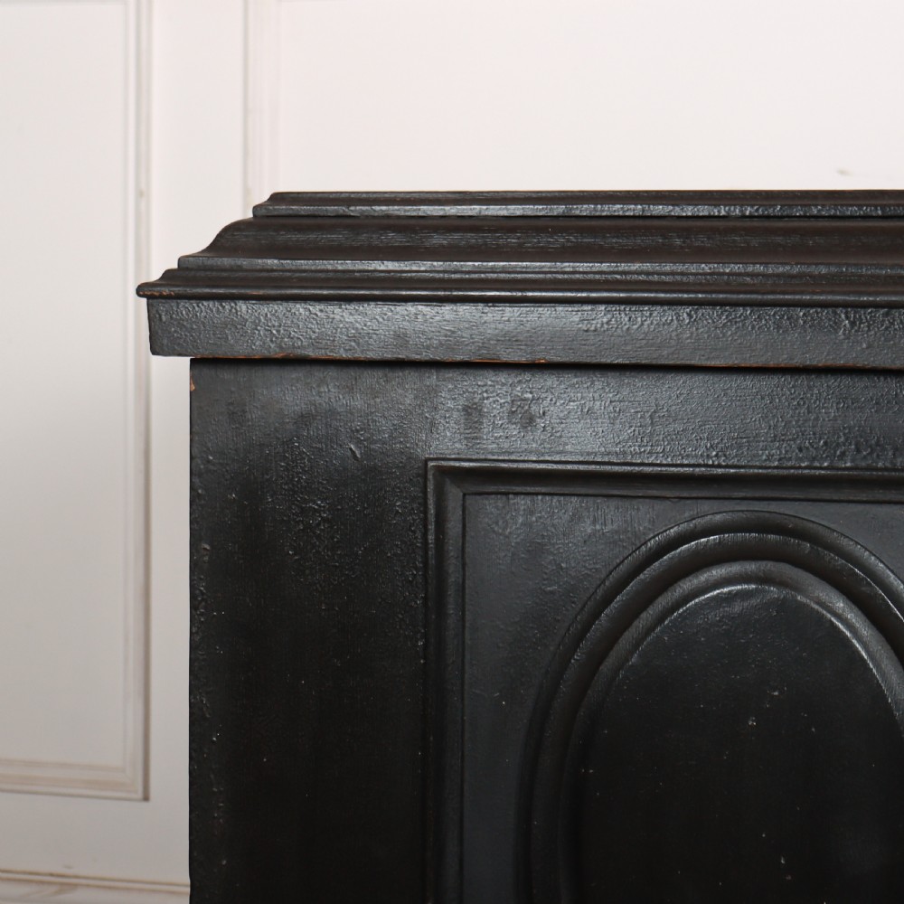 A low black painted wooden credenza featuring three panelled doors with oval mouldings and resting on carved paw feet. View III