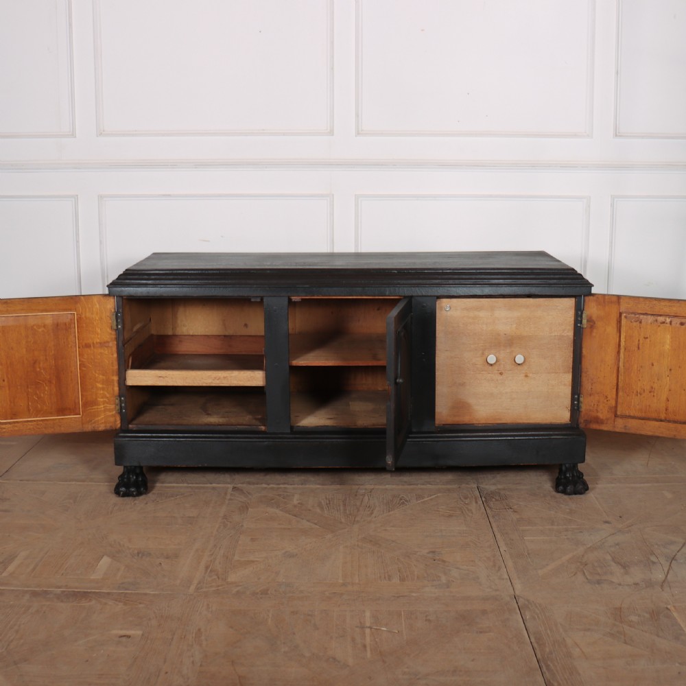 A low black painted wooden credenza featuring three panelled doors with oval mouldings and resting on carved paw feet. View VII
