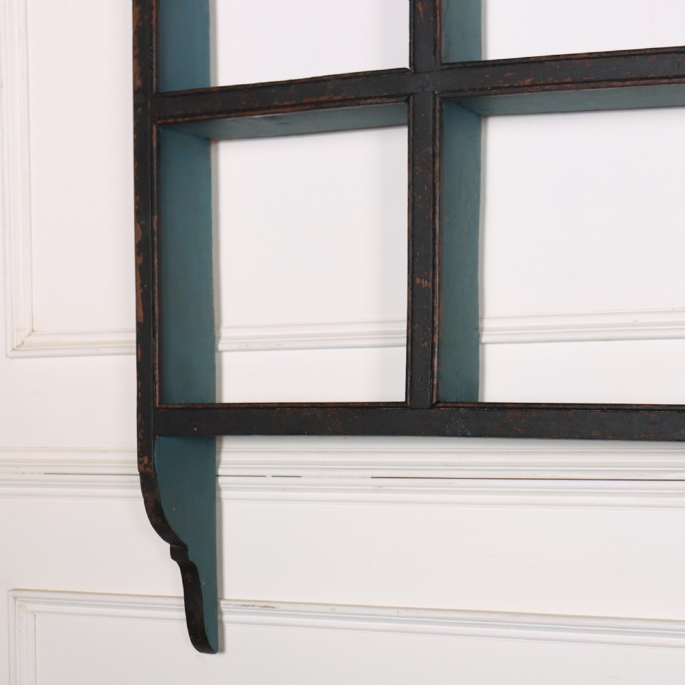 An 18th-century dark painted wooden kitchen dresser base featuring four drawers with brass handles beneath an open wall-mounted plate rack. View IV