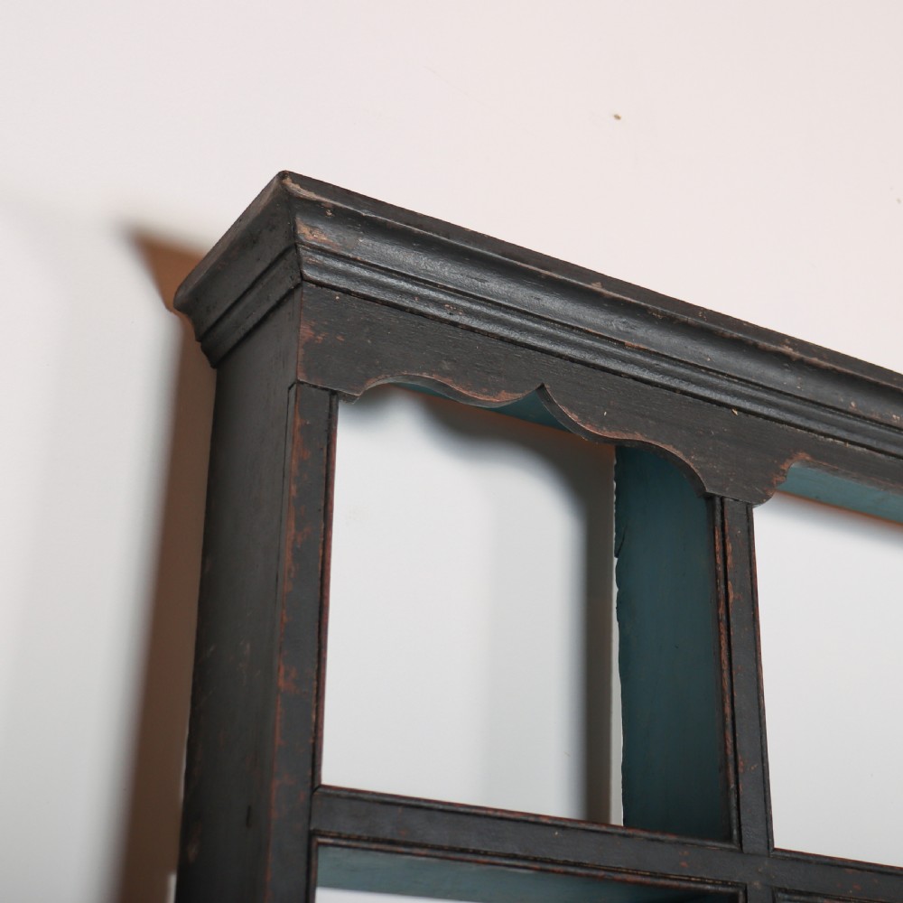 An 18th-century dark painted wooden kitchen dresser base featuring four drawers with brass handles beneath an open wall-mounted plate rack. View VIII
