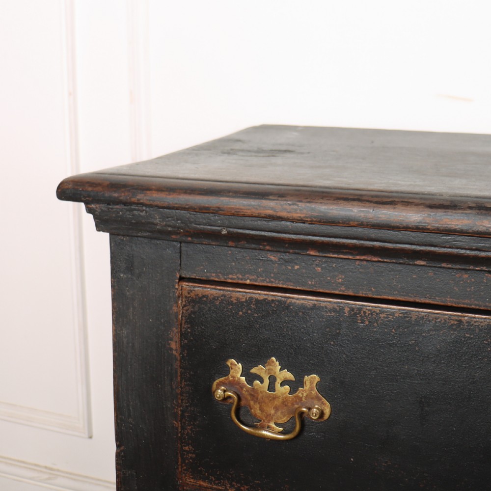 An 18th-century dark painted wooden kitchen dresser base featuring four drawers with brass handles beneath an open wall-mounted plate rack. View XII