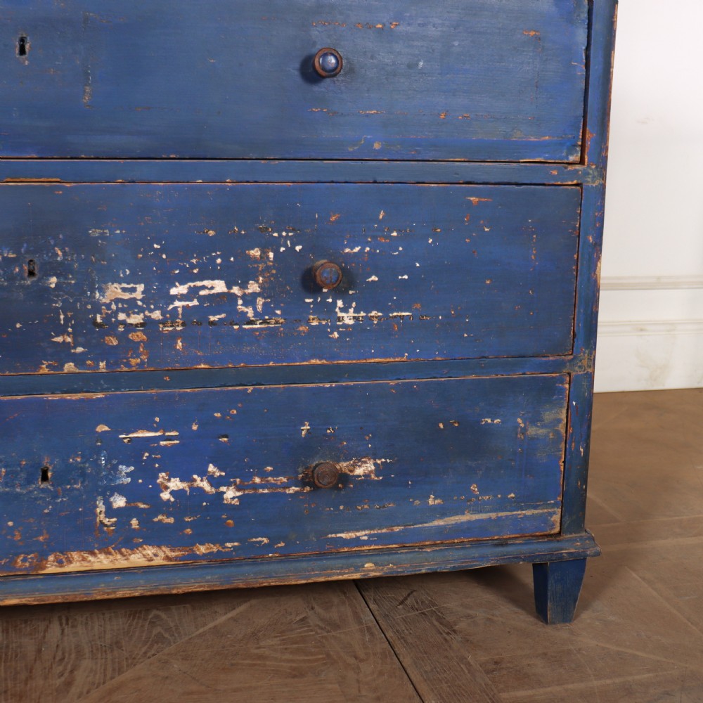 A three-drawer wooden chest of drawers featuring a weathered blue painted finish, small turned knobs, and square tapered feet. View VI