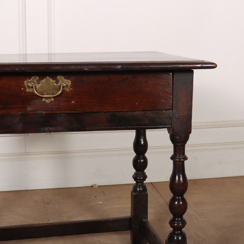 An 18th-century dark oak lamp table featuring turned legs, a single drawer with a brass handle, and low stretchers. View V