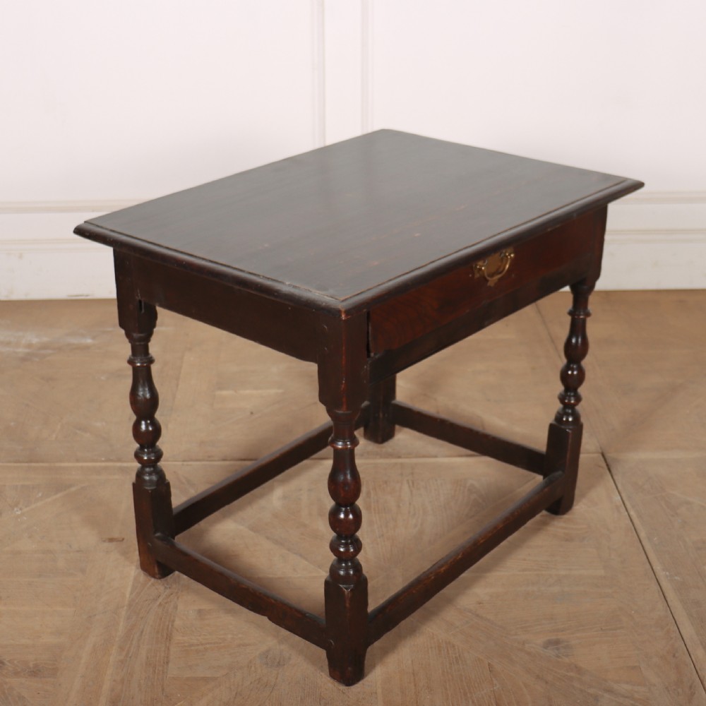 An 18th-century dark oak lamp table featuring turned legs, a single drawer with a brass handle, and low stretchers. View VI