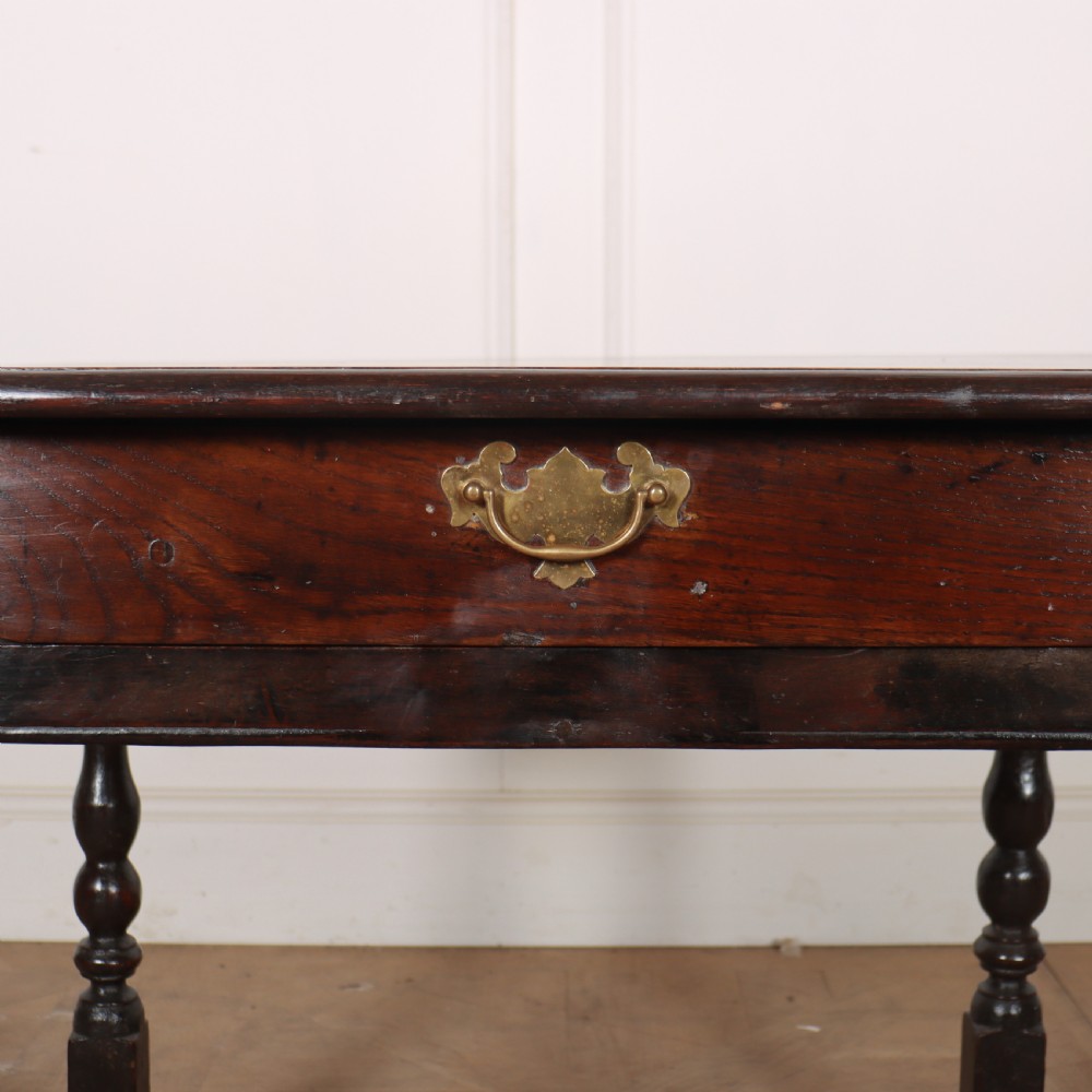 An 18th-century dark oak lamp table featuring turned legs, a single drawer with a brass handle, and low stretchers. View VII