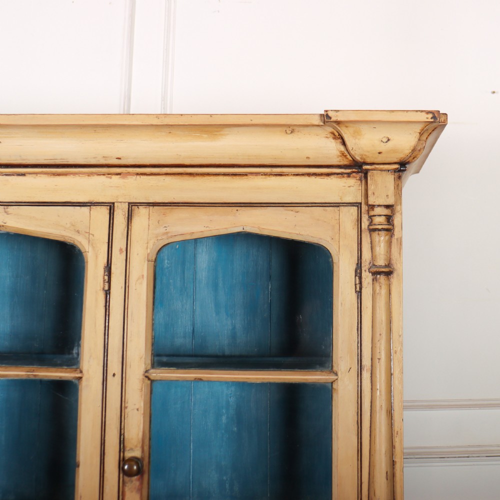 A cream painted timber kitchen dresser featuring a glazed three-door upper display cabinet with a vibrant blue interior above a base with drawers and panelled cupboard doors. View III