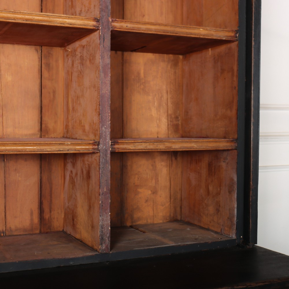 A tall black painted antique bookcase featuring three upper doors with gold-tone brass lattice grilles over three solid panelled lower cupboard doors. View X