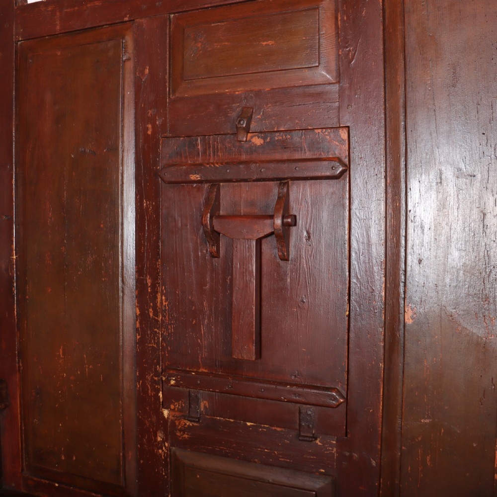 An 18th-century Spanish high-backed settle crafted from dark reddish-brown painted wood with raised back panels and integrated armrests. View IV
