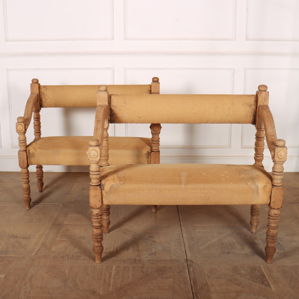 Pair of French bleached oak settles with turned legs, carved rosette details, and neutral canvas upholstery.