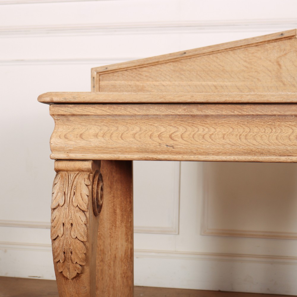 A light tan bleached oak console table with a low pedimented upstand and carved acanthus leaf front legs. View II