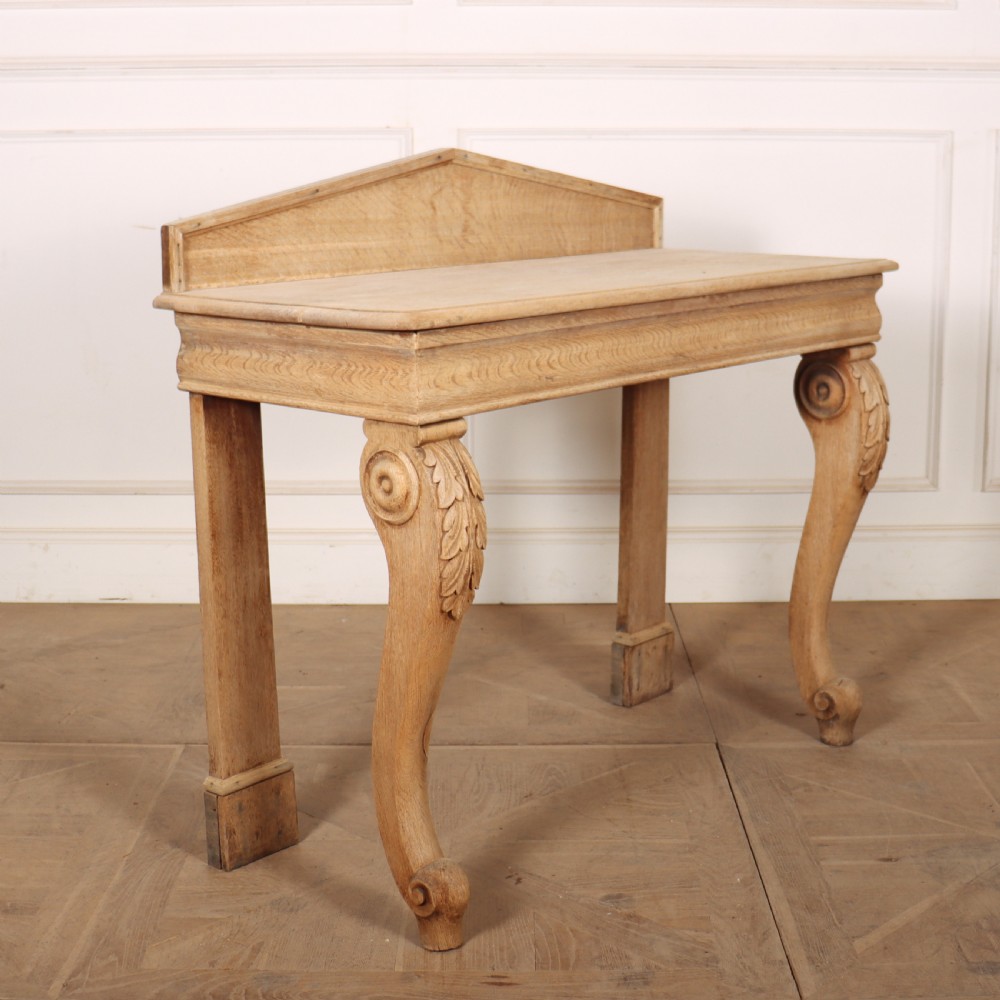 A light tan bleached oak console table with a low pedimented upstand and carved acanthus leaf front legs. View VI