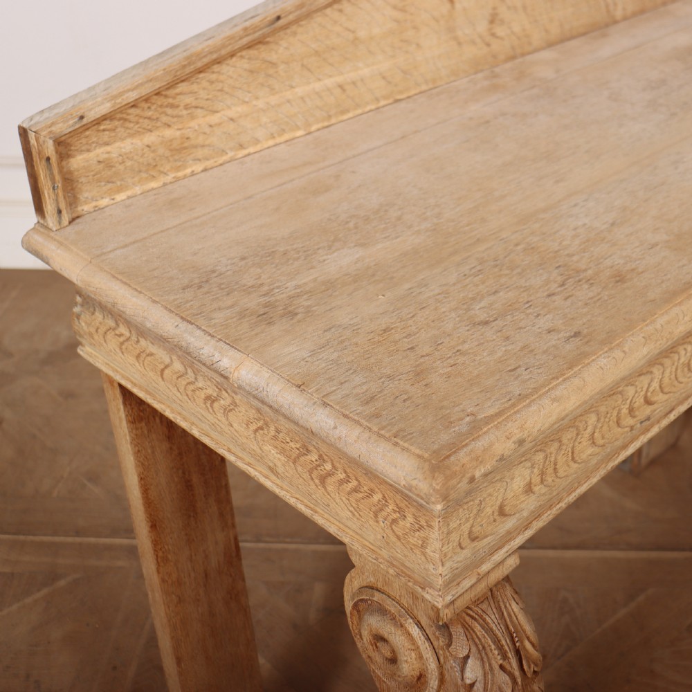 A light tan bleached oak console table with a low pedimented upstand and carved acanthus leaf front legs. View VII