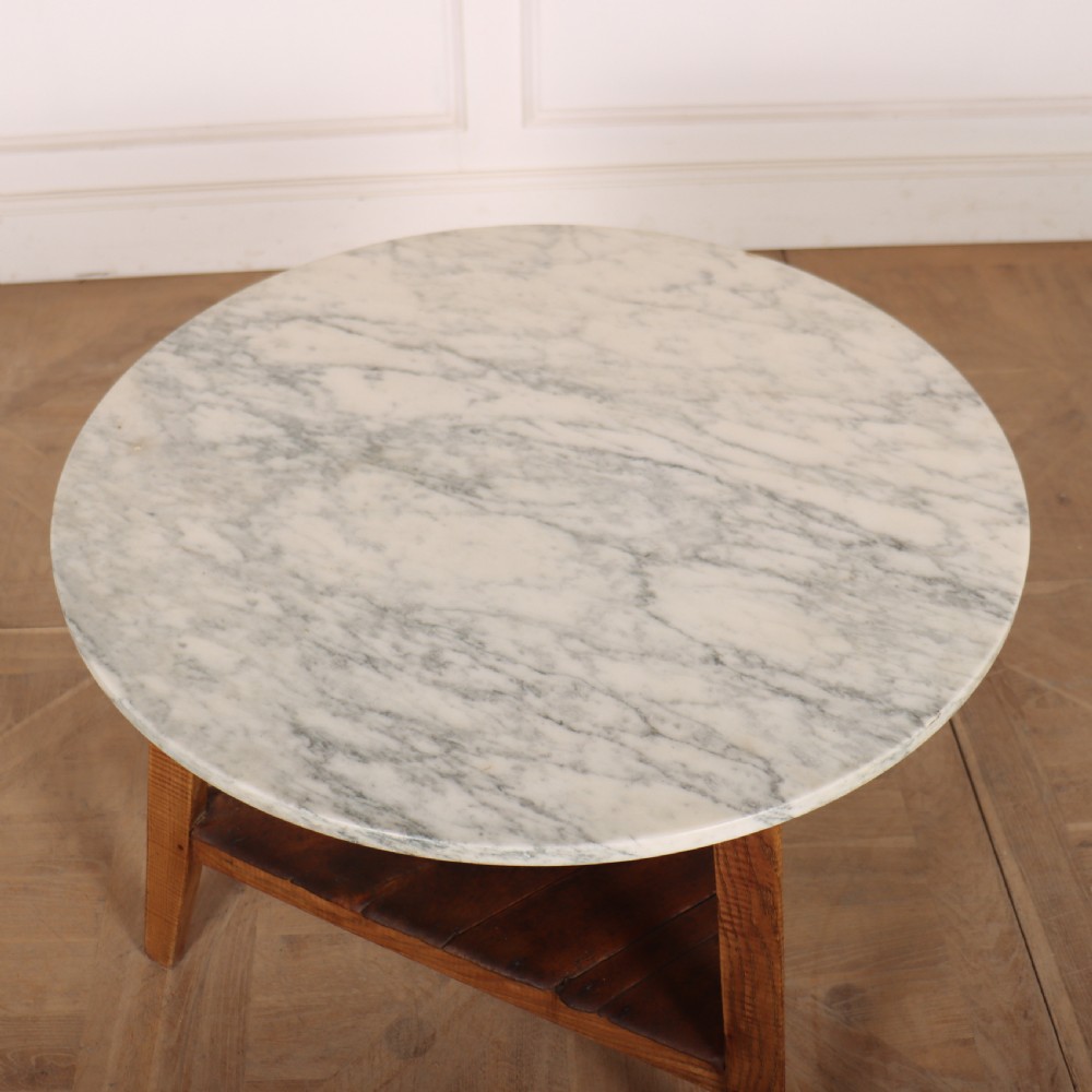 A nineteenth-century Welsh cricket table featuring a circular white marble top supported by a three-legged wooden frame with a lower triangular shelf. View III