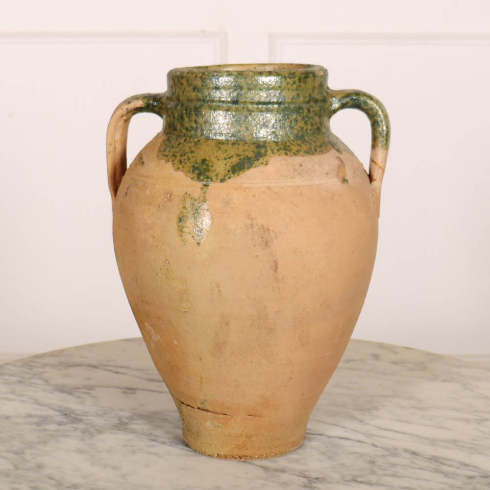 A two-handled terracotta water pot featuring an unglazed buff body and a green glaze around the rim and neck.