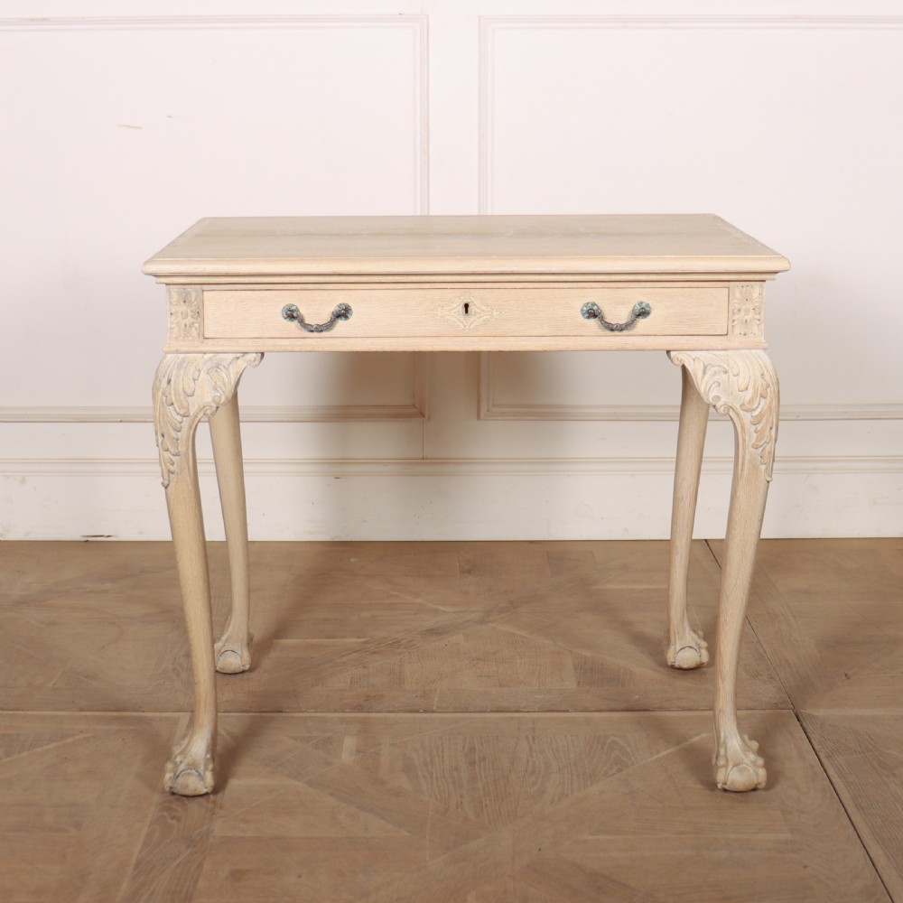 A bleached oak lamp table featuring carved cabriole legs with claw-and-ball feet, acanthus knee carvings, and a single drawer with twin brass drop handles.