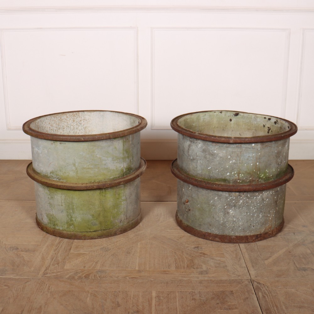 A pair of cylindrical weathered zinc planters featuring rusty iron rims and mid-bands with a distressed aged finish.