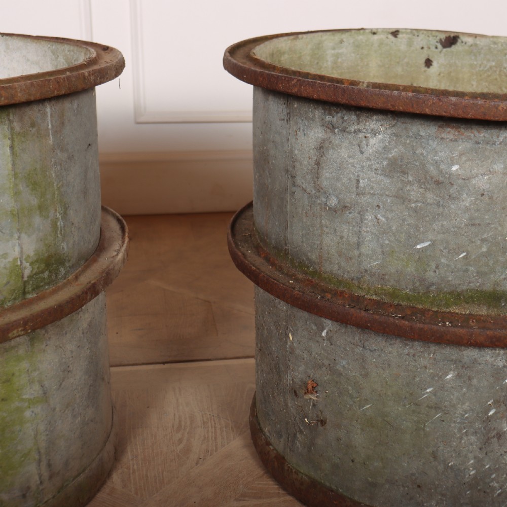 A pair of cylindrical weathered zinc planters featuring rusty iron rims and mid-bands with a distressed aged finish. View VI