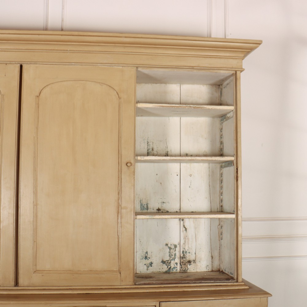 A large two-part painted pine housekeepers cupboard featuring three upper arched-panel doors above three central drawers flanked by side cupboards. View III