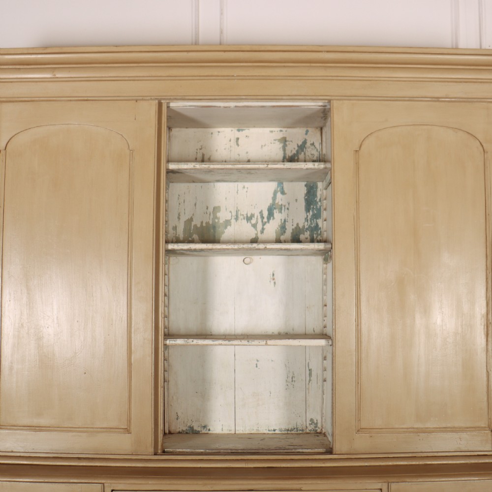 A large two-part painted pine housekeepers cupboard featuring three upper arched-panel doors above three central drawers flanked by side cupboards. View IV