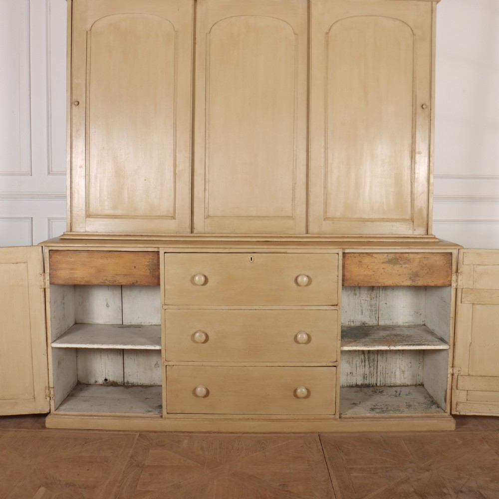 A large two-part painted pine housekeepers cupboard featuring three upper arched-panel doors above three central drawers flanked by side cupboards. View V