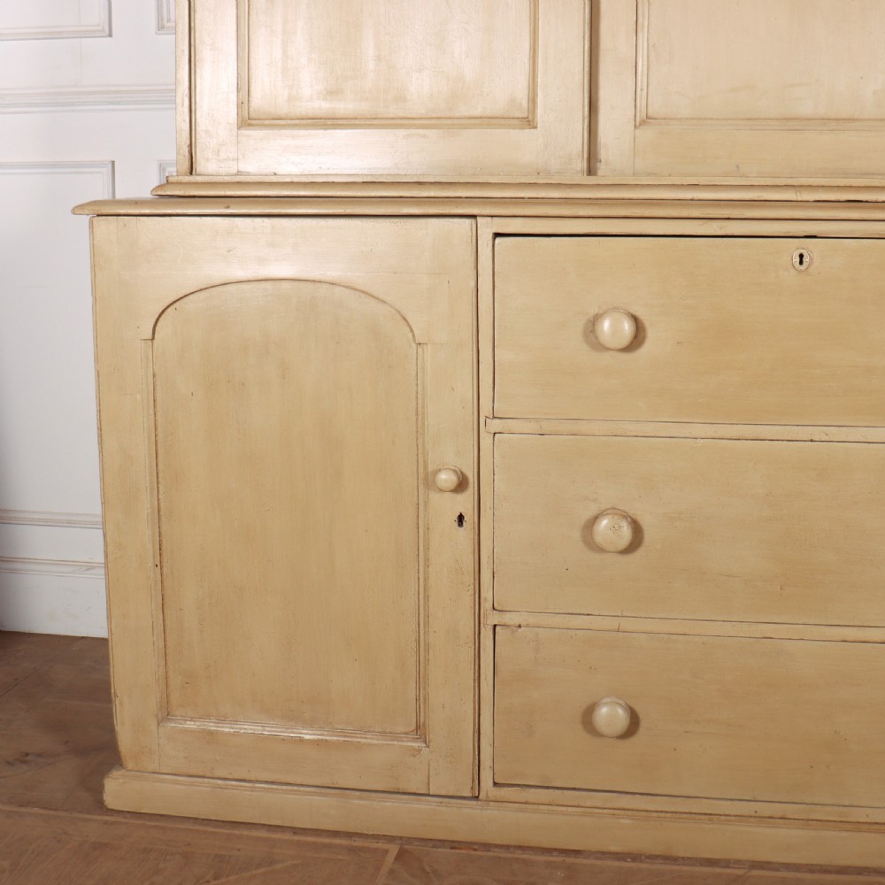 A large two-part painted pine housekeepers cupboard featuring three upper arched-panel doors above three central drawers flanked by side cupboards. View VI