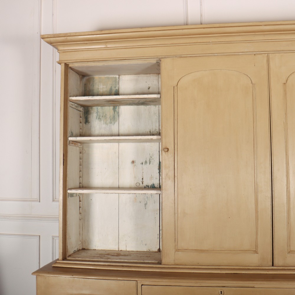 A large two-part painted pine housekeepers cupboard featuring three upper arched-panel doors above three central drawers flanked by side cupboards. View VII