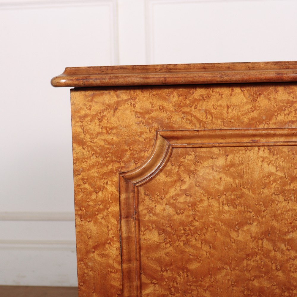 A golden brown burr elm bedside cabinet featuring a single panelled cupboard door and a solid plinth base. View II
