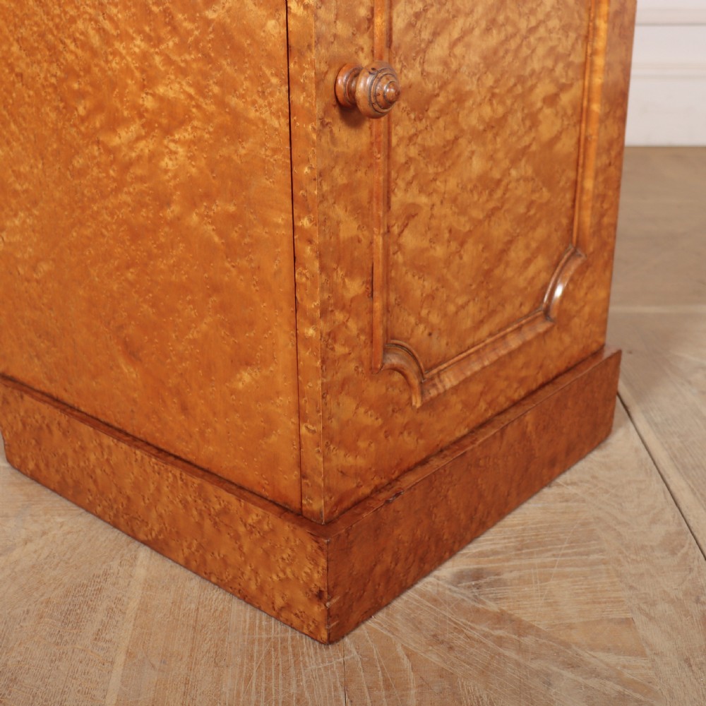 A golden brown burr elm bedside cabinet featuring a single panelled cupboard door and a solid plinth base. View IV