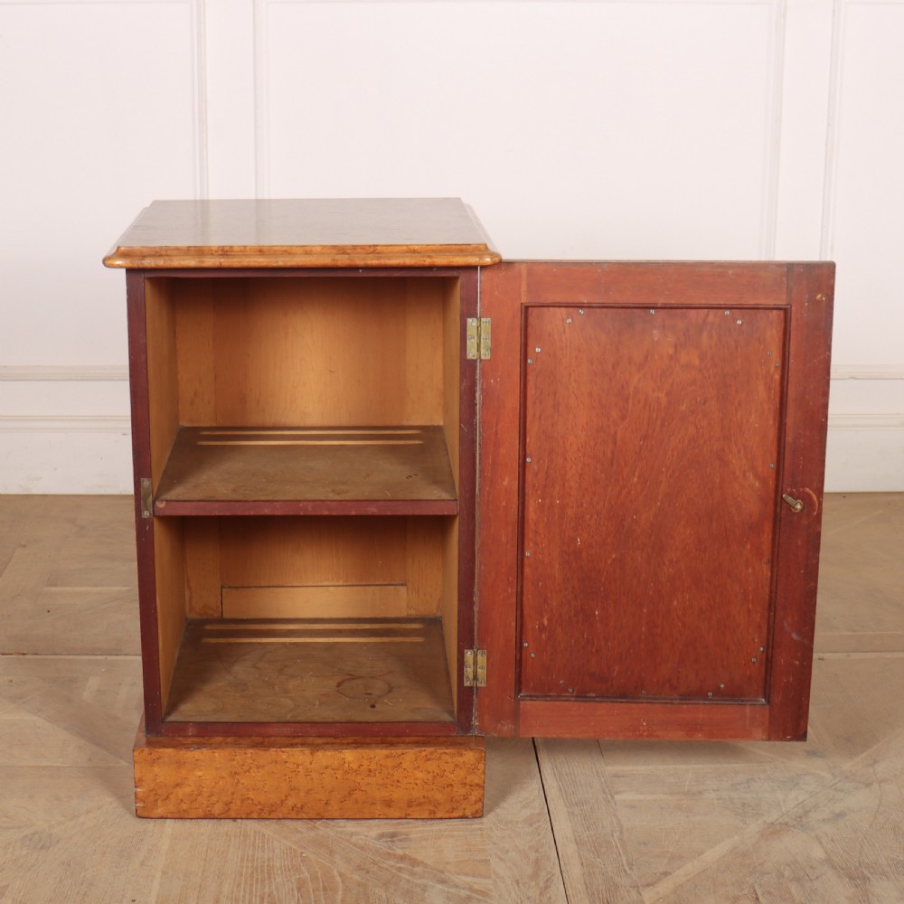 A golden brown burr elm bedside cabinet featuring a single panelled cupboard door and a solid plinth base. View V