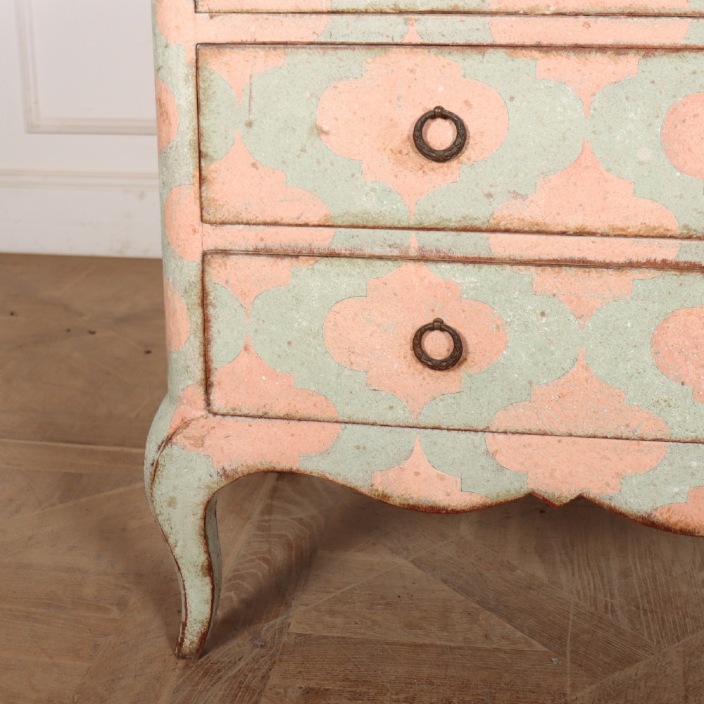 An Italian style three-drawer painted wooden commode featuring a pastel pink and green geometric pattern, brass ring pulls, and a terracotta marble top. View III