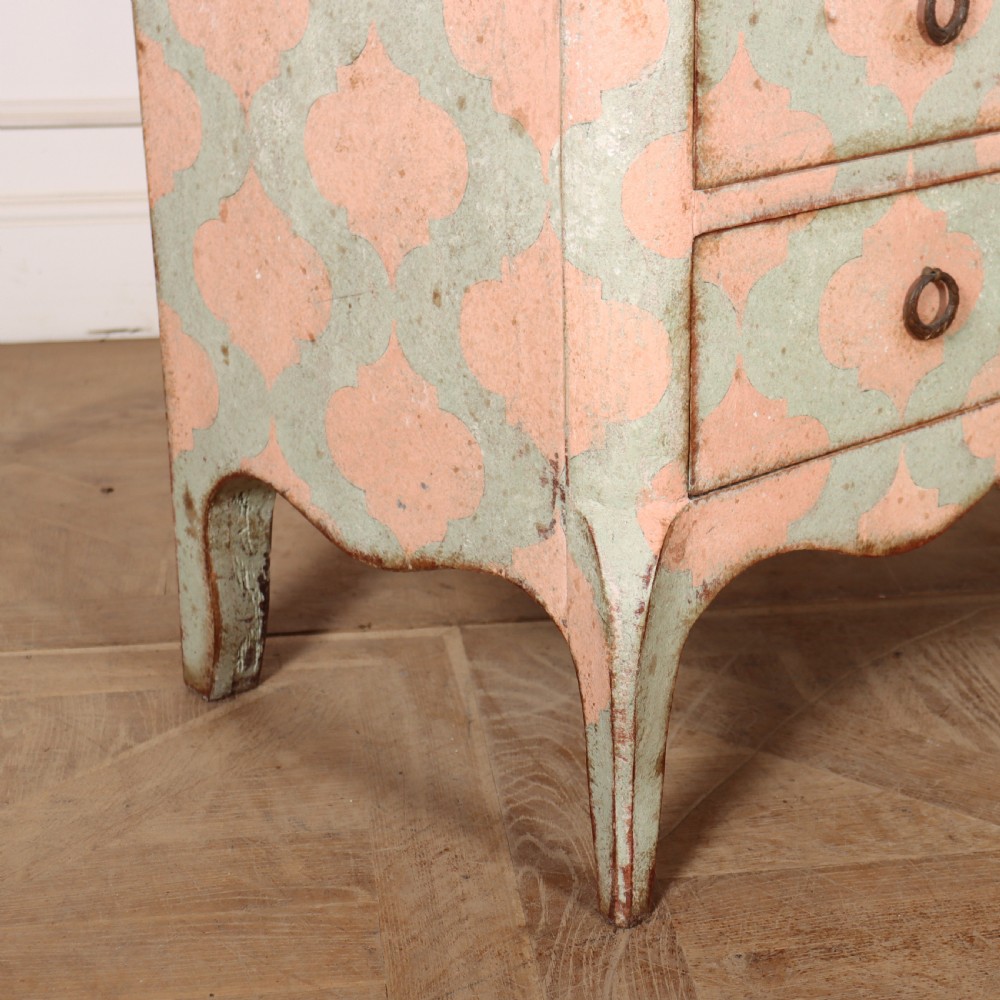 An Italian style three-drawer painted wooden commode featuring a pastel pink and green geometric pattern, brass ring pulls, and a terracotta marble top. View IX