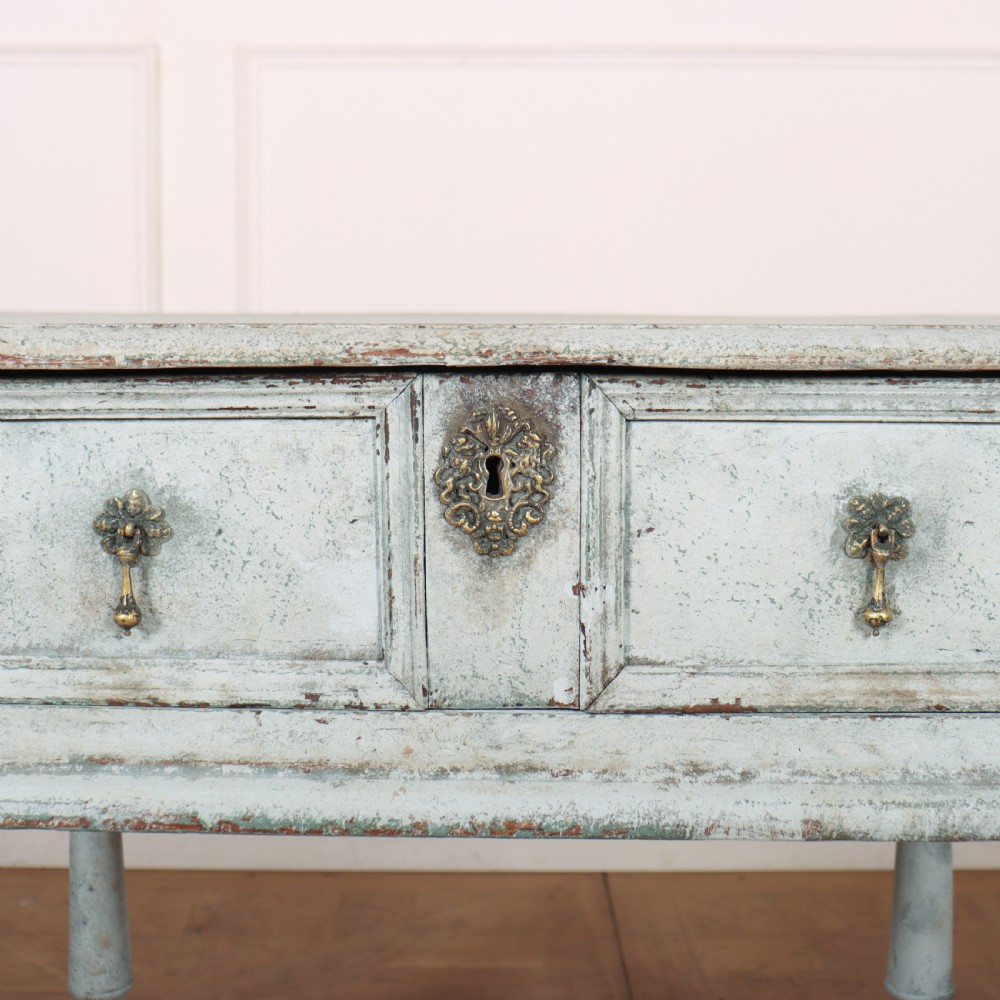 An 18th-century painted wooden side table featuring a pale blue distressed surface, turned legs, an X-frame stretcher, and two drawer fronts with brass pulls. View IV