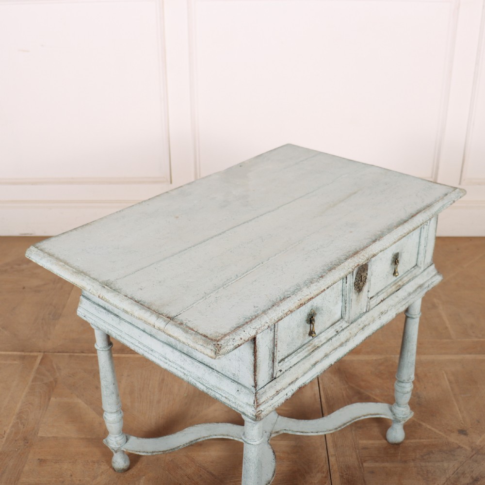 An 18th-century painted wooden side table featuring a pale blue distressed surface, turned legs, an X-frame stretcher, and two drawer fronts with brass pulls. View V