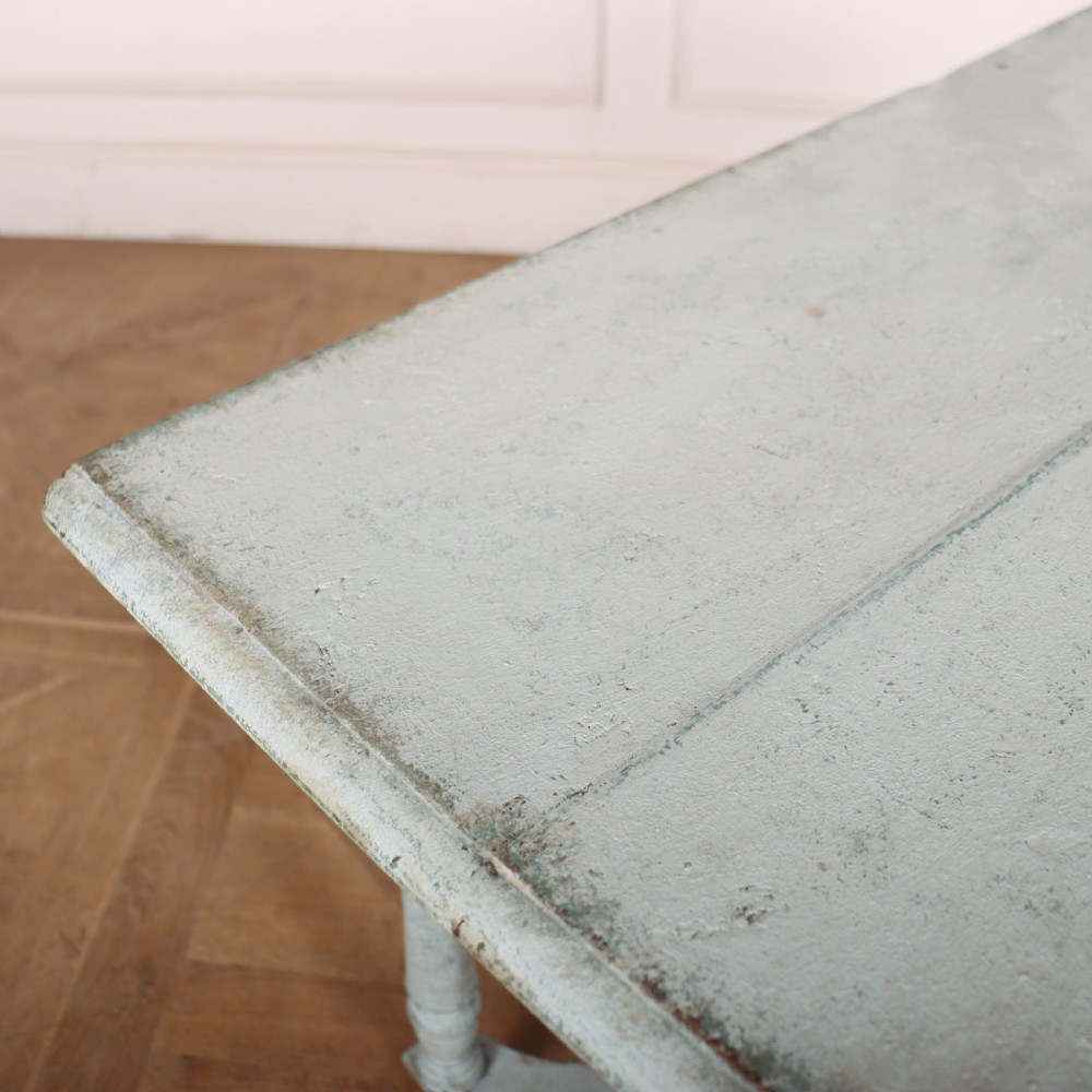 An 18th-century painted wooden side table featuring a pale blue distressed surface, turned legs, an X-frame stretcher, and two drawer fronts with brass pulls. View VI