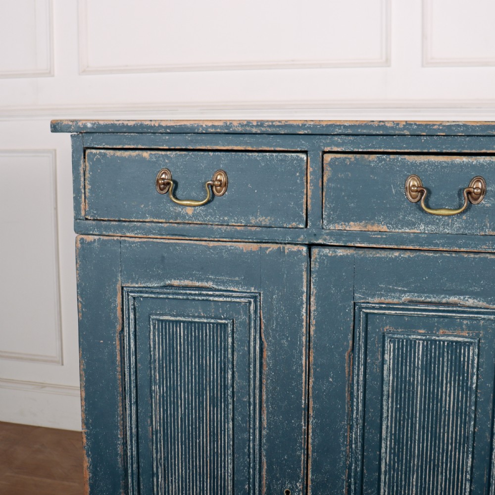 An antique Swedish four-door cupboard featuring a distressed blue painted finish, four top drawers with brass drop handles, and reeded vertical panel doors. View II
