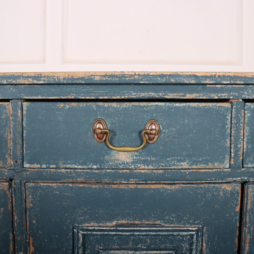 An antique Swedish four-door cupboard featuring a distressed blue painted finish, four top drawers with brass drop handles, and reeded vertical panel doors. View VII
