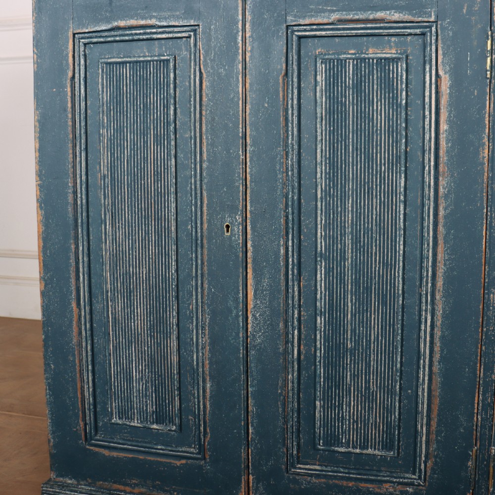 An antique Swedish four-door cupboard featuring a distressed blue painted finish, four top drawers with brass drop handles, and reeded vertical panel doors. View VIII