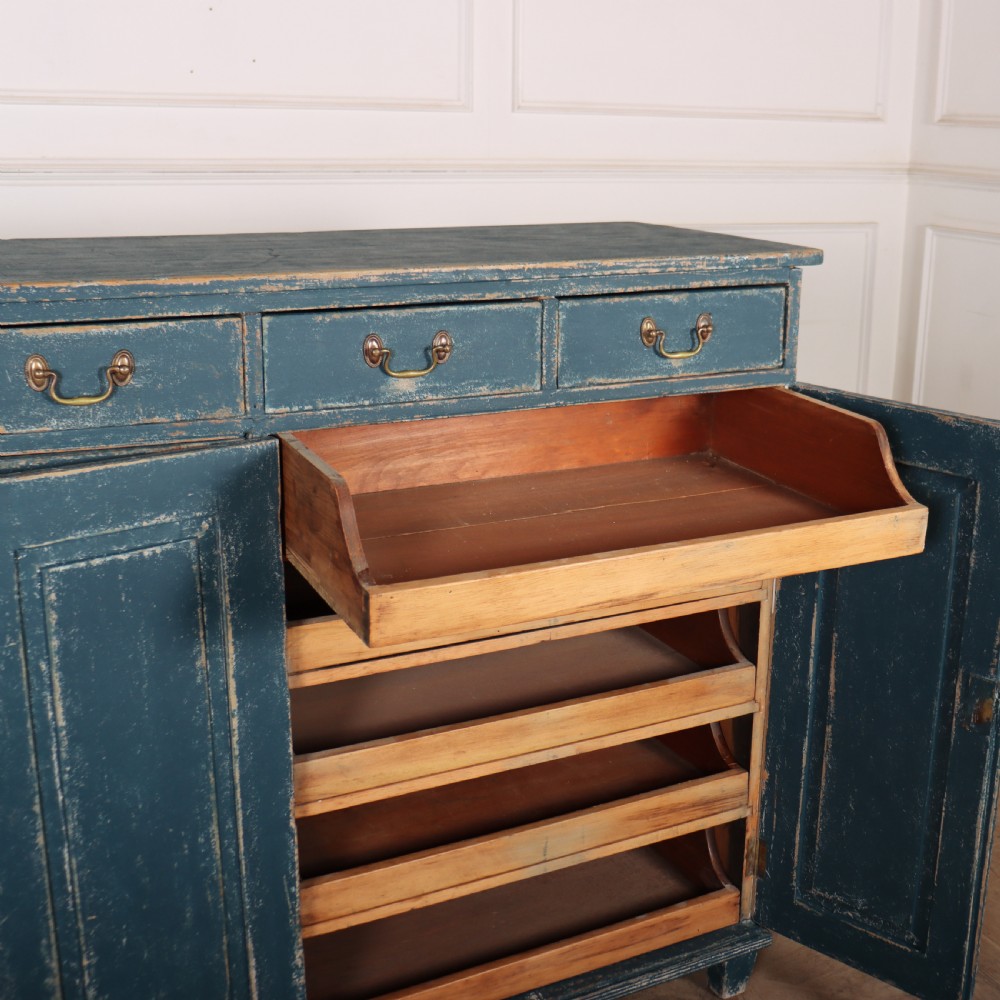 An antique Swedish four-door cupboard featuring a distressed blue painted finish, four top drawers with brass drop handles, and reeded vertical panel doors. View IX