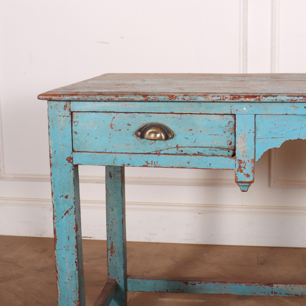 A rectangular wooden table with distressed light blue paint, featuring two drawers with brass cup handles and a low stretcher base. View II