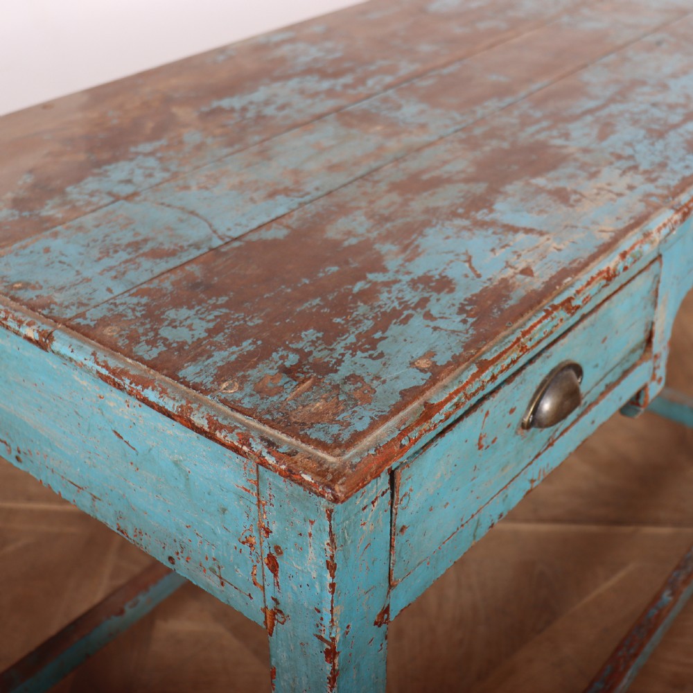 A rectangular wooden table with distressed light blue paint, featuring two drawers with brass cup handles and a low stretcher base. View VII