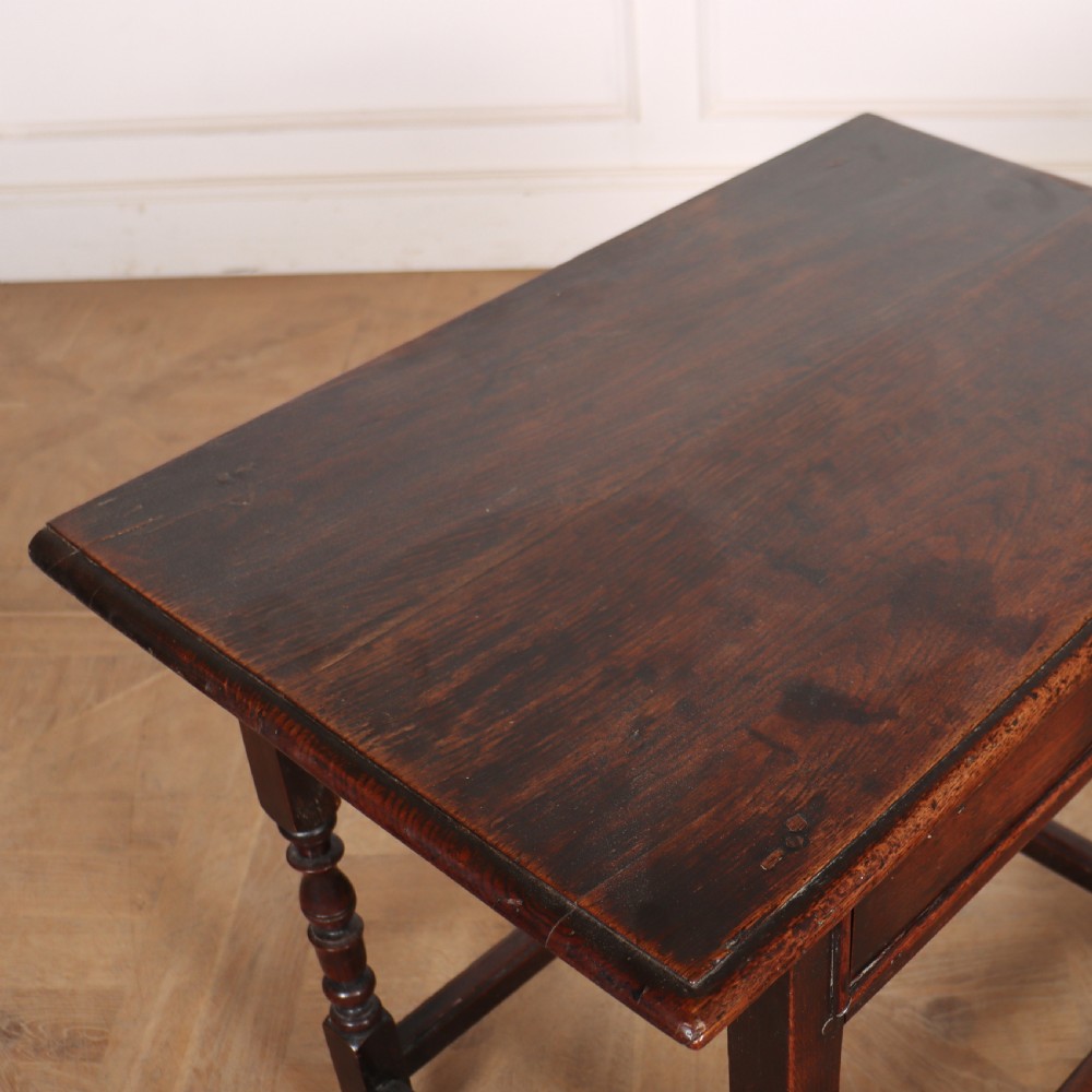 A dark oak 17th-century lamp table featuring a single drawer with a teardrop brass handle, turned baluster legs, and lower box stretchers. View IV