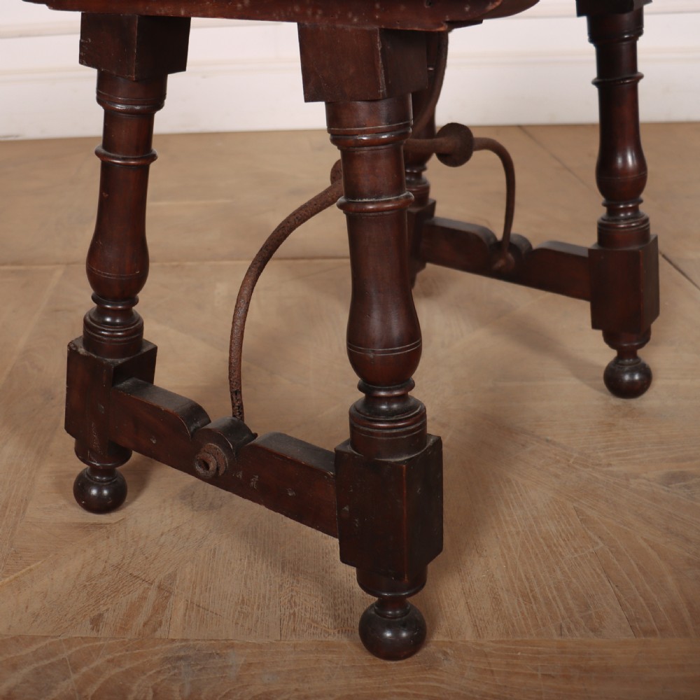 A dark walnut side table featuring turned legs supported by a curved wrought iron stretcher. View III