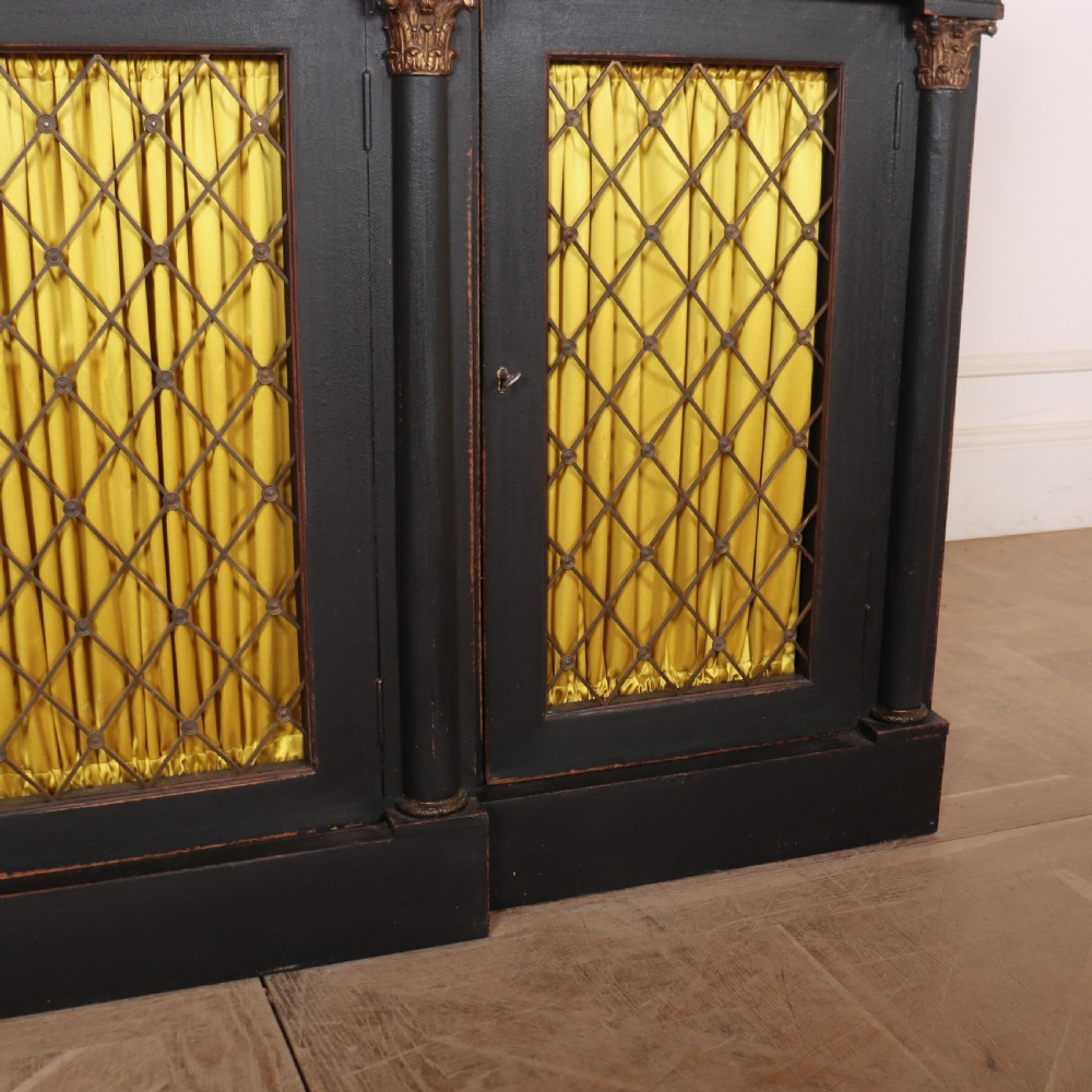 A painted English Regency breakfront dresser base featuring a green marble top, four frieze drawers, Corinthian columns, and mesh doors backed with yellow silk. View II