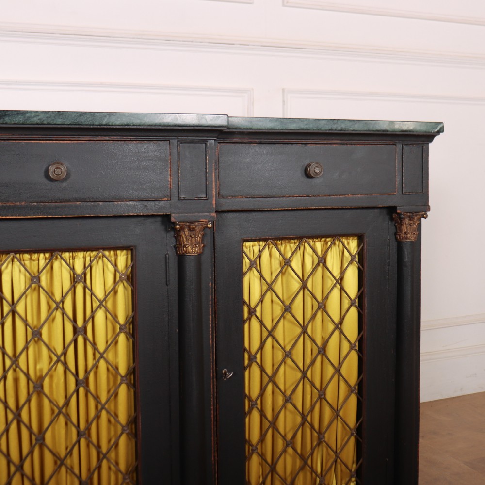A painted English Regency breakfront dresser base featuring a green marble top, four frieze drawers, Corinthian columns, and mesh doors backed with yellow silk. View III