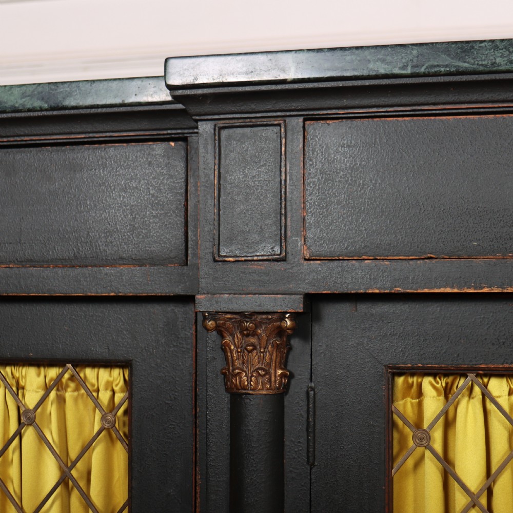 A painted English Regency breakfront dresser base featuring a green marble top, four frieze drawers, Corinthian columns, and mesh doors backed with yellow silk. View IV