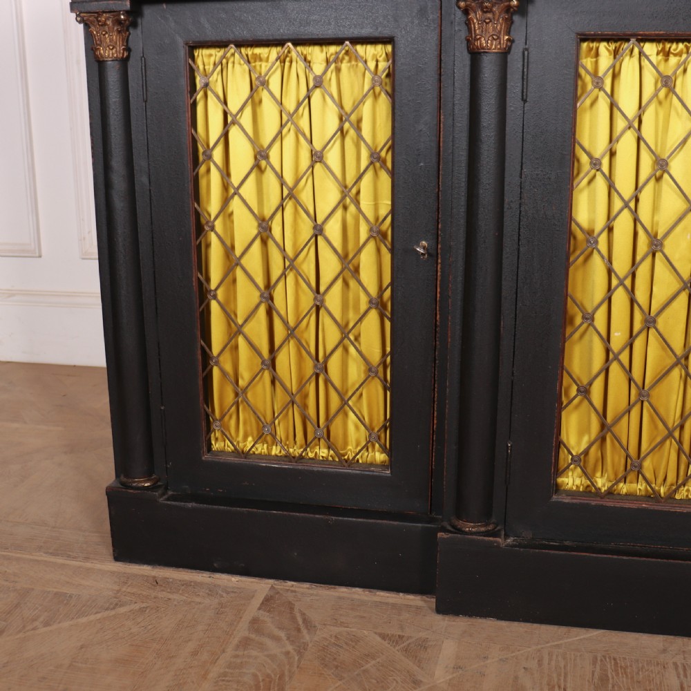 A painted English Regency breakfront dresser base featuring a green marble top, four frieze drawers, Corinthian columns, and mesh doors backed with yellow silk. View V