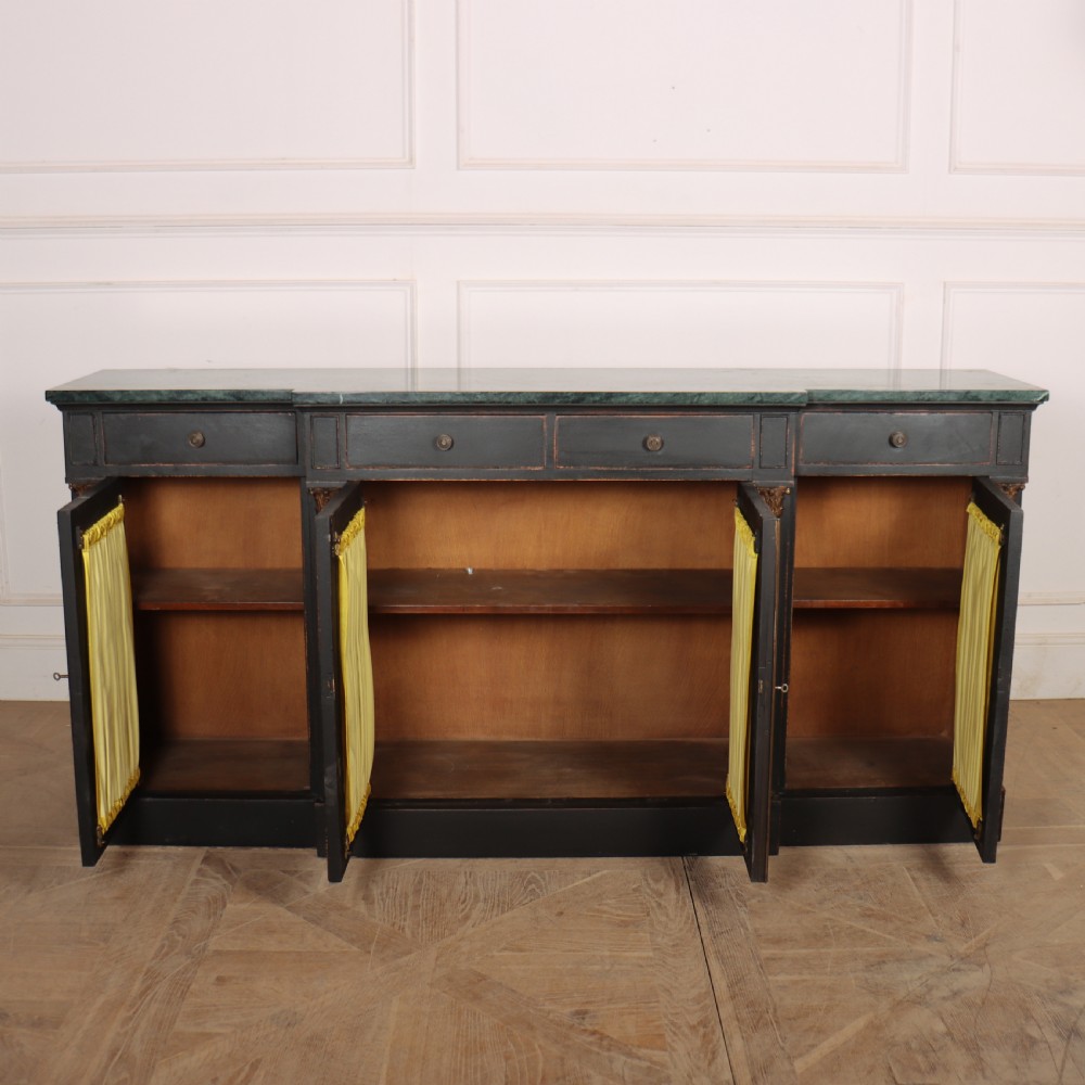 A painted English Regency breakfront dresser base featuring a green marble top, four frieze drawers, Corinthian columns, and mesh doors backed with yellow silk. View IX