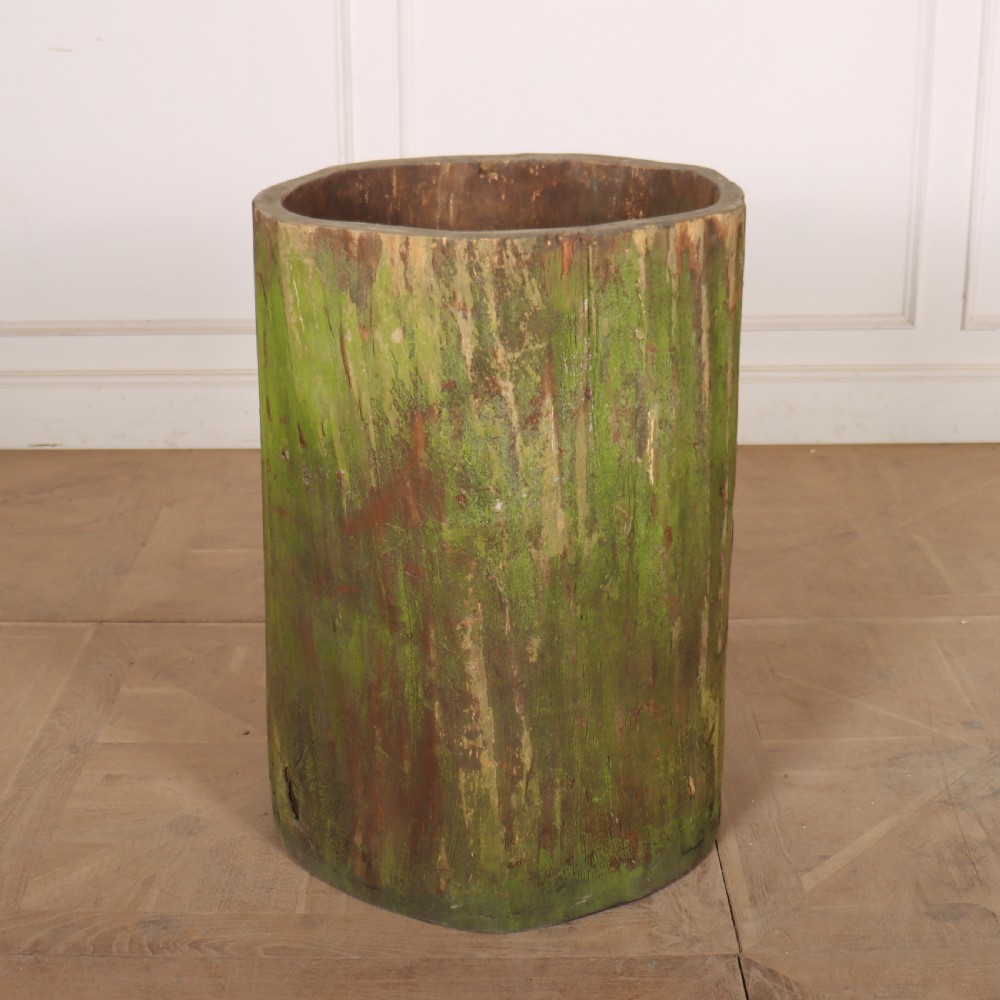 A vertical hollowed-out sycamore log planter with a weathered brown timber exterior and green patina highlights. View IV