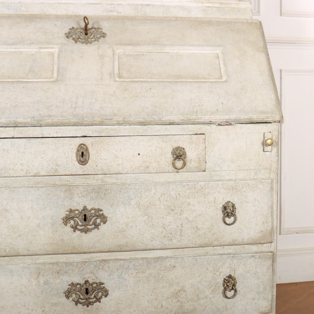 An off-white painted Danish bureau bookcase with a gallery-topped upper cupboard, stepped side drawers, a slant-front desk, and lower drawers fitted with brass lion-head ring handles. View IV