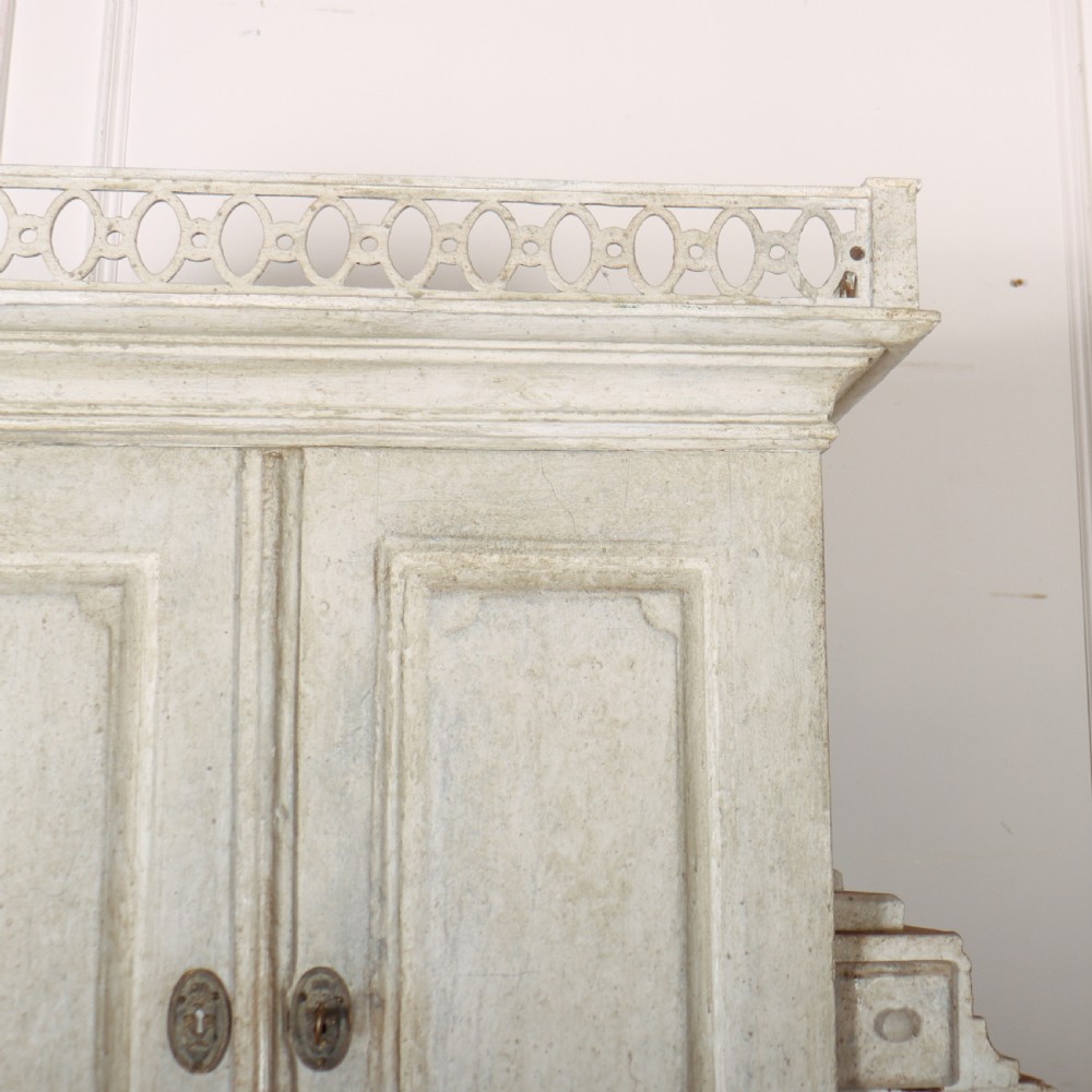 An off-white painted Danish bureau bookcase with a gallery-topped upper cupboard, stepped side drawers, a slant-front desk, and lower drawers fitted with brass lion-head ring handles. View VII
